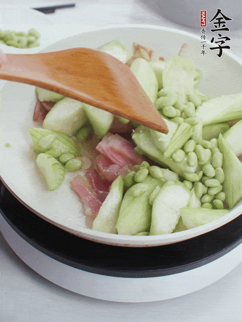 依次下絲瓜、青豆翻炒，炒至絲瓜打蔫縮小。