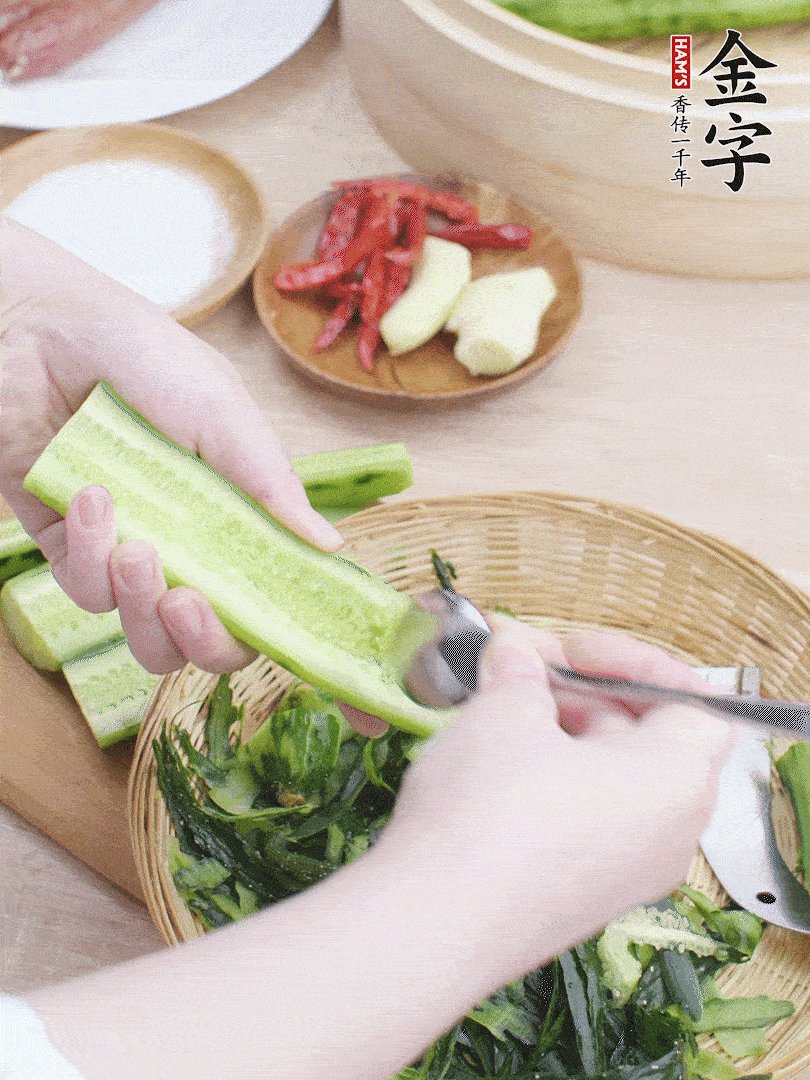 黃瓜削皮，對半切開，勺子挖去內(nèi)瓤，斜刀切片。青蒜斜刀切段。